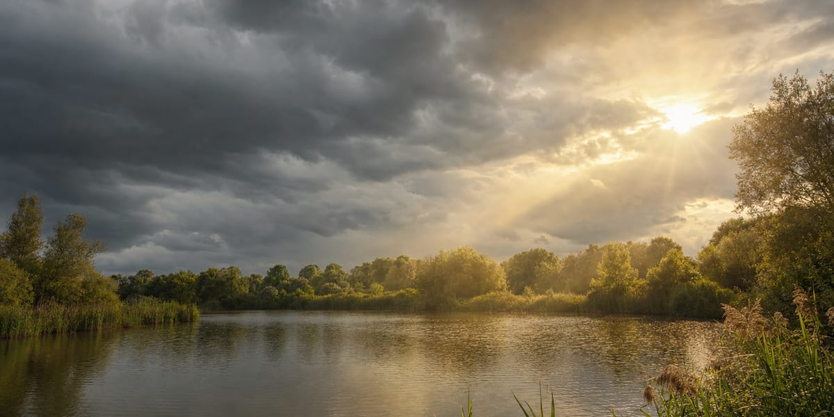 A UK carp lake under a changing sky with sun breaking through storm cloud